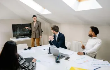 Sala donde se encuentran varias personas delante de una pantalla viendo gráficos sobre finanzas