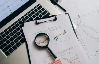 encima de un escritorio hay un ordenador junto con estadísticas y una lupa