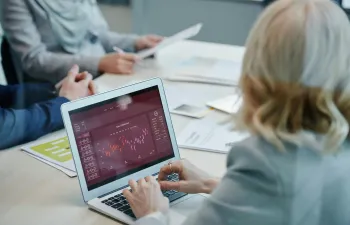 una empresaria está sentada en su escritorio viendo estadísticas en su ordenador