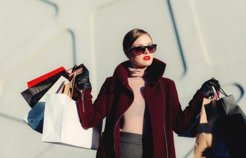 una cleinta está saliendo de una tienda de ropa con muchas bolsas en la mano