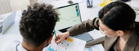 dos compañeros de trabajo están leyendo un informe de finanzas