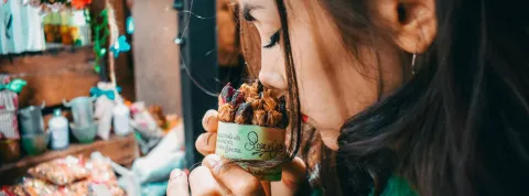 Una chica esta en un comercio oliendo un pasteñ