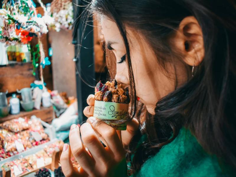 Una chica esta en un comercio oliendo un pasteñ