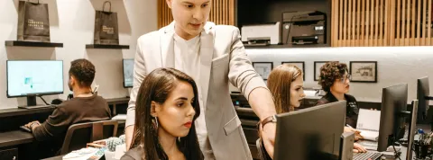 Dos trabajadores están en una oficina mirando al ordenador