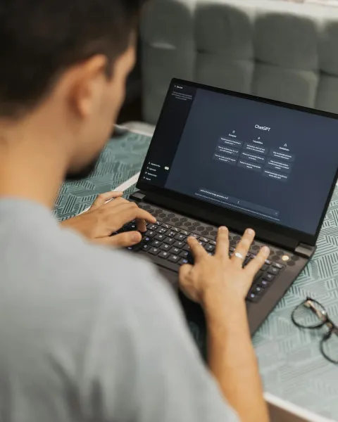 Un chico joven está con su ordenador utilizando un chatbot
