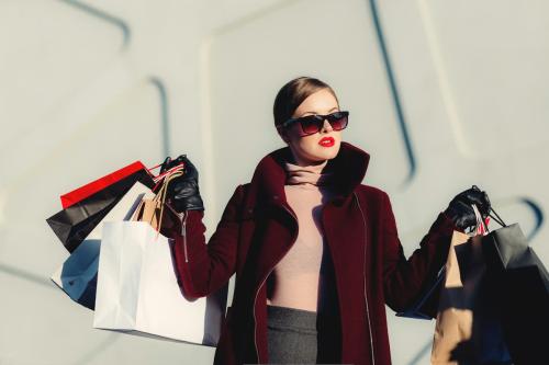 una cleinta está saliendo de una tienda de ropa con muchas bolsas en la mano