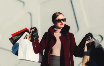 una cleinta está saliendo de una tienda de ropa con muchas bolsas en la mano