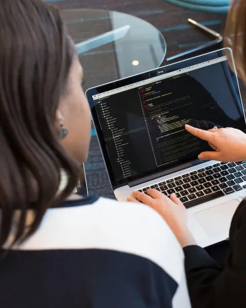 dos compañeras de trabajo están viendo códigos de programación en el ordenador