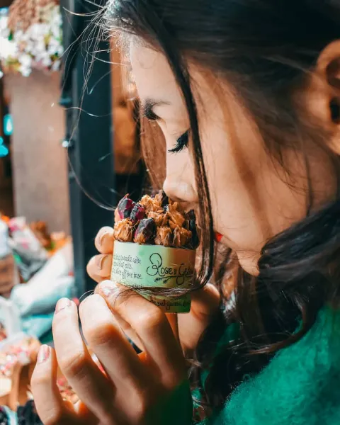 Una chica esta en un comercio oliendo un pasteñ