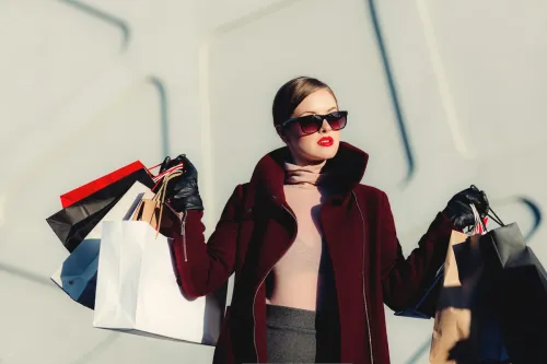 una cleinta está saliendo de una tienda de ropa con muchas bolsas en la mano